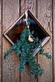 Bird ornament with evergreen garland on wooden front door of Tregaron home Wales UK