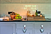 Lit tealights with apples and nuts on grey kitchen worktop with silver hearts in Tregaron home Wales UK