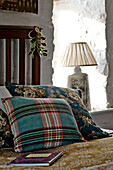 Checked and floral cushions with holly on wooden bed in Tregaron home Wales UK