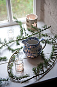 Chinaware jug with pine needles and tealights on windowsill of Tregaron home Wales UK
