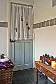 Linen bathroom door curtain with lit candle on wooden side table in Tregaron home Wales UK