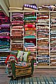 Abgenutzter Ledersessel mit gefalteten walisischen Decken in einem Geschäft in Tregaon, Wales, Großbritannien