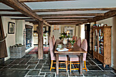 Checked dining chairs at table in beamed room with flagstone floor Sherford barn conversion Devon UK