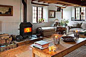 Lit wood burning stove with tealights on coffee table in living room of Sherford barn conversion Devon UK