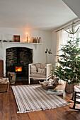Christmas tree and armchair with wood burning stove in Crantock home Cornwall England UK