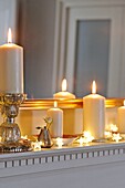 Angezündete Kerzen und Lichterketten auf dem Kaminsims im Haus der Familie in Penzance, Cornwall, England, UK
