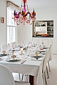 Beaded glass chandelier above dining table with service hatch in Penzance family home Cornwall England UK