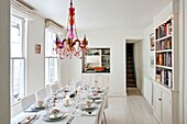 Beaded glass chandelier above dining table with service hatch and bookcase in Penzance family home Cornwall England UK