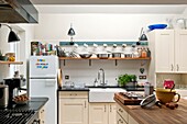 Cups and saucepans on shelving in kitchen of Penzance family home Cornwall England UK