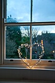 Beleuchtetes Herz auf der Fensterbank eines Familienhauses in Penzance Cornwall England UK