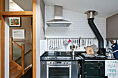 Utensil rail above oven and hob at wooden doorway in modern kitchen, Cornwall, UK