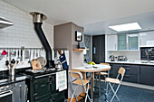 Folding chairs at table with range oven in modern kitchen of Cornwall home UK