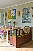 Salvaged bench seat at kitchen table with artwork in East Grinstead family home West Sussex England UK