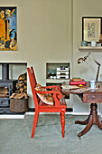 Rot gestrichener Stuhl am Schreibtisch mit Lampe im Wohnzimmer eines Familienhauses in East Grinstead, West Sussex, England, Vereinigtes Königreich