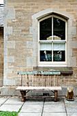 Weathered bench seat below window of old stone Stamford home Lincolnshire England UK