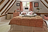 Double bed at window in timber framed attic bedroom of Cambridge cottage England UK