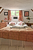 Double bed below window in timber framed bedroom of Cambridge cottage England UK