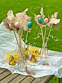 Easter eggs and feathers in milk bottles on Sussex garden table England UK