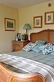 Wicker bed with gilt-framed artwork in Edworth bedroom Bedfordshire England UK