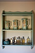 Ceramic jugs and perfume bottles on wall-mounted shelving in Edworth bathroom Bedfordshire England UK