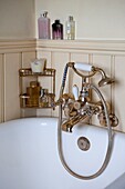 Brass shower fitting and toiletries in tongue and groove Edworth bathroom Bedfordshire England UK