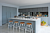 Wooden barstools in spacious modern kitchen of Lechlade home Gloucestershire England UK