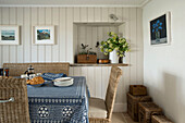 Frühstückstisch mit blauem Tischtuch und Korbstühlen in einer Bauernhausküche in Penzance, Cornwall, England, UK
