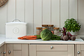Fresh vegetables with breadbin in panelled kitchen of Penzance farmhouse Cornwall England UK