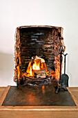 Hearth set at lit fireside in family townhouse Cornwall England UK