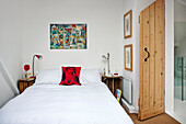 Kunstwerk über einem Doppelbett mit Seitenlampen und Holztür in einem Stadthaus in Cornwall England UK
