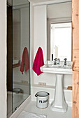 Red towel beside pedestal basin with flour bin in family townhouse Cornwall England UK