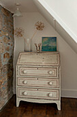 Cream painted writing bureau with exposed stone wall in Cornwall cottage UK