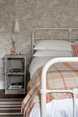 Tartan blanket on double bed with patterned wallpaper and bedside table Cornwall UK