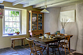 Wooden chairs and dresser with table set for afternoon in Helston farmhouse kitchen Cornwall UK