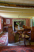 Altmodische Sitzbank und Tisch aus Holz mit gemusterten Teppichen in einem Bauernhaus in Helston, Cornwall UK