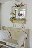 White cushions on painted bench below vintage mirror in Marazion beach house Cornwall UK
