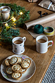 Festive snacks and wrapping paper with evergreen foliage on wooden table St Erth Cornwall UK