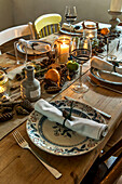 Candles fruit and vintage plates with napkins and pinecones at Christmas St Erth Cornwall UK