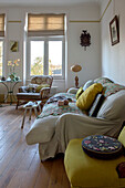 Tapestry cushion on yellow chair with cream sofa in London apartment UK