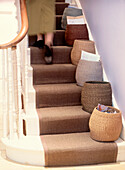Woman walking upstairs past storage baskets on staircase