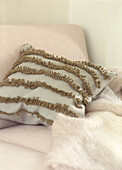 Sofa detail with blue woolen cushion with applied green fringe stripes and mohair throw