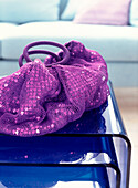 Purple sequined net handbag on a nest of blue Perspex side tables in living room