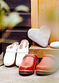 Red and white wooden clogs on a doorstep outside of wooden building