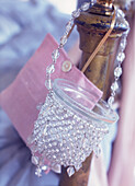 Nahaufnahme eines perlenbesetzten Nachtlichts und einer hübschen rosa Tasche, die an einem hölzernen Bettpfosten hängt
