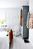 Vintage clothes hang in Lyme Regis bedroom with wardrobe and rocking chair Dorset UK