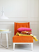 Assorted fabrics and pink cushion on orange chair