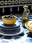 Schwarze Oliven in Keramikschale mit blau-weißen Tellern und Vinaigrette Marokko Nordafrika