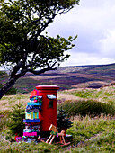 Stack of Christmas presents and letter with rocking horse at postbox in remote Scottish farmland UK
