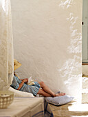 Frau mit Sonnenhut im weiß getünchten Innenhof einer spanischen Villa
