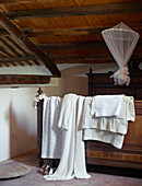 Blankets and dressing gown with mosquito net on mezzanine bed in Sicilian home